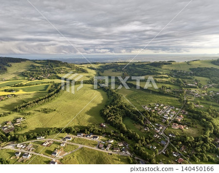 Rural hillside landscape with scattered homes and winding roads under cloudy sky Rural hillside landscape with scattered homes and winding roads under cloudy sky 140450166