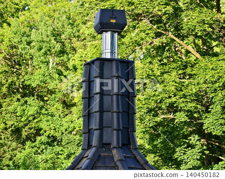 Dark tiled turret roof with metal chimney against forest Dark tiled turret roof with metal chimney against forest 140450182