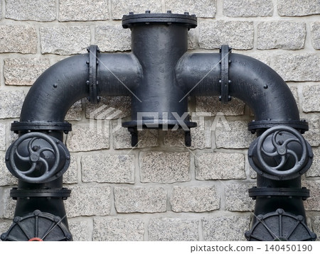 Black cast iron water pipe assembly mounted on stone wall Black cast iron water pipe assembly mounted on stone wall 140450190