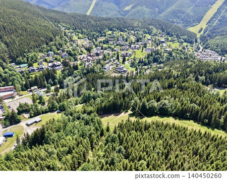 Aerial view of mountain village surrounded by dense evergreen forest Aerial view of mountain village surrounded by dense evergreen forest 140450260