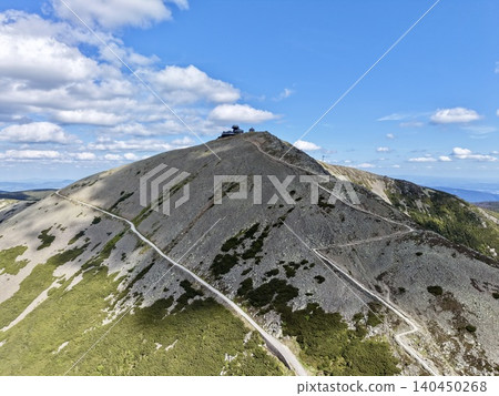 Mountain summit with winding hiking trails under blue sky Mountain summit with winding hiking trails under blue sky 140450268