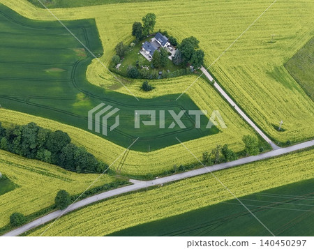 Aerial view of farmhouse surrounded by patchwork crop fields and winding country road Aerial view of farmhouse surrounded by patchwork crop fields and winding country road 140450297