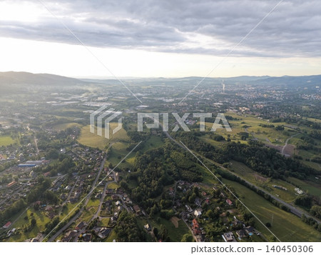 Aerial view of rolling green hills and suburban valley under cloudy sky Aerial view of rolling green hills and suburban valley under cloudy sky 140450306