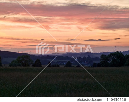 Sunset over rolling rural fields with distant tree lined horizon 140450316