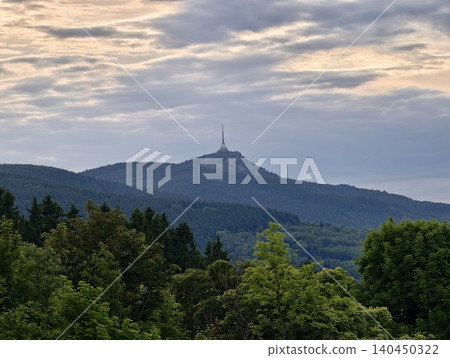 Distant mountain peak with transmission tower above forested ridgelines at dusk Distant mountain peak with transmission tower above forested ridgelines at dusk 140450322