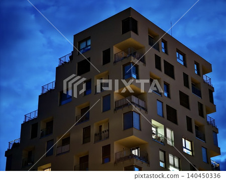 Modern apartment building at dusk with illuminated windows 140450336