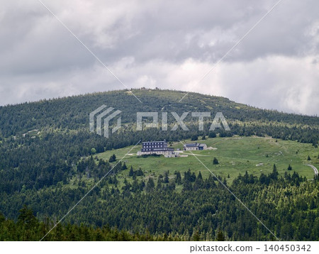 Mountain lodge on a grassy alpine ridge under cloudy sky 140450342