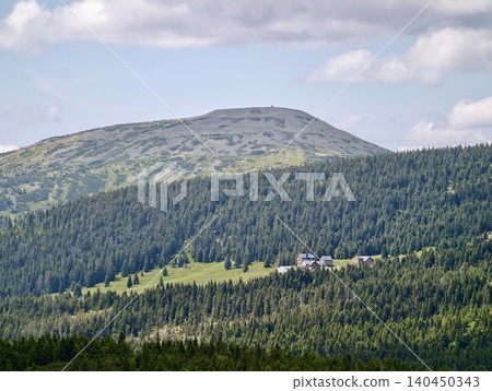Mountain lodge nestled in dense evergreen forest beneath rounded summit Mountain lodge nestled in dense evergreen forest beneath rounded summit 140450343