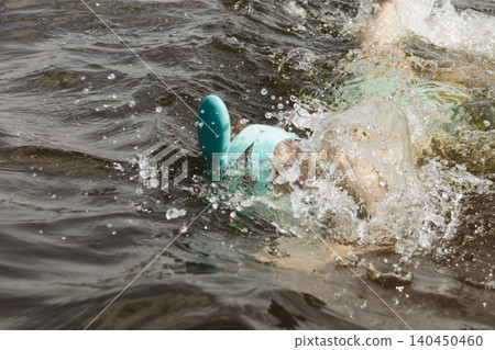cheerful close up boy splashing through shallow water wearing turquoise snorkeling mask, expressing delight and approval. Family vacation water safety, children's sports equipment, or summer leisure. cheerful close up boy splashing through shallow water wearing turquoise snorkeling mask, expressing delight and approval. Family vacation water safety, children's sports equipment, or summer leisure. 140450460
