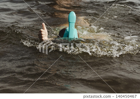 cheerful close up boy in shallow water wearing turquoise snorkeling mask. child gives two thumbs up, expressing delight approval. Family vacations, water safety, children's sports equipment, summer 140450467