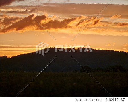 Golden sunset sky over dark hillside landscape 140450487