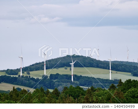 Wind turbines on green hills under a cloudy sky Wind turbines on green hills under a cloudy sky 140450499