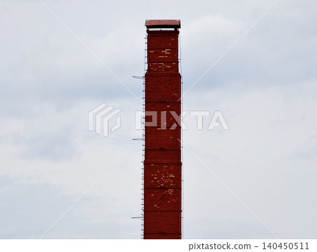 Red industrial chimney against a cloudy sky 140450511