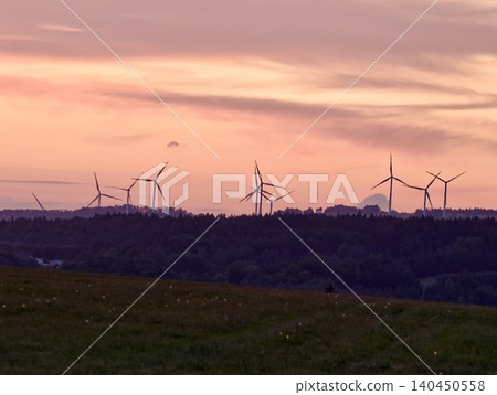 Wind turbines silhouetted against a warm sunset sky over a rural landscape Wind turbines silhouetted against a warm sunset sky over a rural landscape 140450558