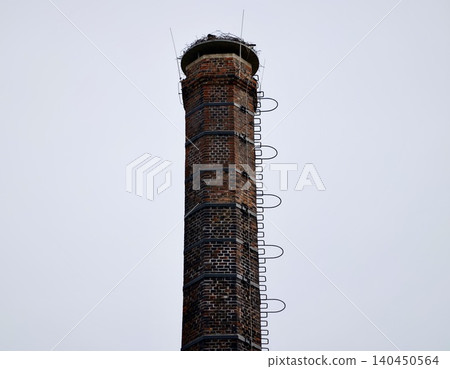 Tall brick chimney with metal ladder against cloudy sky Tall brick chimney with metal ladder against cloudy sky 140450564