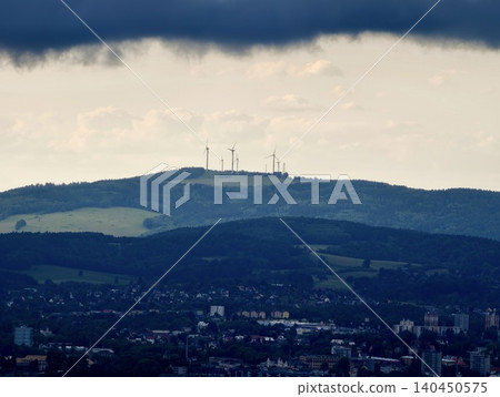 Wind turbines on a distant ridge above a town under dramatic storm clouds Wind turbines on a distant ridge above a town under dramatic storm clouds 140450575