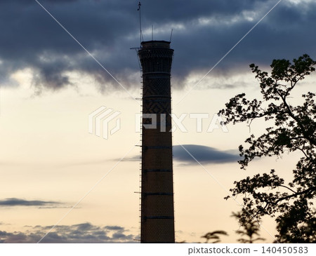 Tall industrial chimney against a dramatic cloudy sky Tall industrial chimney against a dramatic cloudy sky 140450583