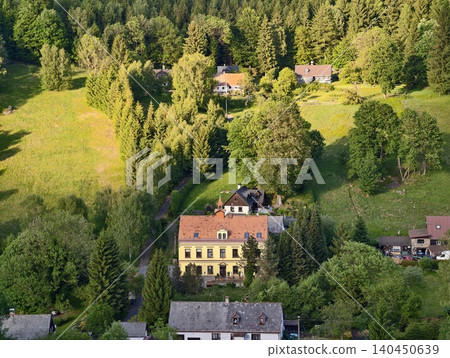 Yellow country manor surrounded by forested hillside and cottages Yellow country manor surrounded by forested hillside and cottages 140450639