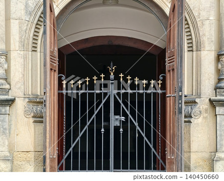 Ornate arched stone entrance with wooden doors and wrought iron gate Ornate arched stone entrance with wooden doors and wrought iron gate 140450660