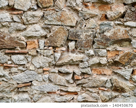 Weathered stone wall with exposed brick fragments Weathered stone wall with exposed brick fragments 140450670