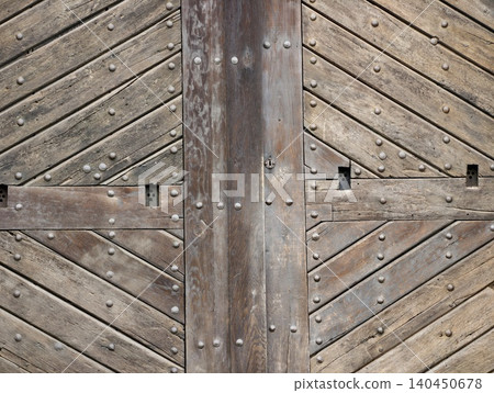 Weathered wooden gate with diagonal planks and iron studs Weathered wooden gate with diagonal planks and iron studs 140450678