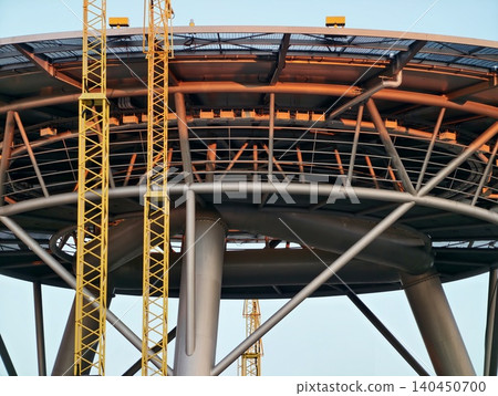 Close-up of steel platform and support columns under construction with yellow cranes 140450700