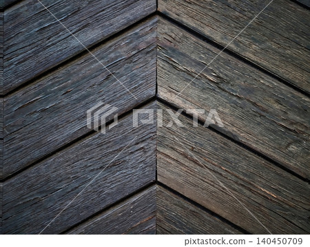 Weathered wooden chevron siding with pronounced grain and dark tones Weathered wooden chevron siding with pronounced grain and dark tones 140450709