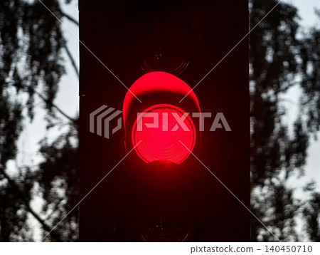 Red traffic signal glowing against a dark pole at dusk Red traffic signal glowing against a dark pole at dusk 140450710