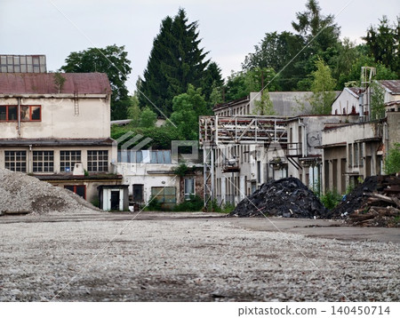 Abandoned industrial yard with derelict factory buildings and rubble piles Abandoned industrial yard with derelict factory buildings and rubble piles 140450714