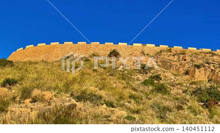 A Historic Fortress Wall Stands Majestically Against a Clear and Expansive Blue Sky Above A Historic Fortress Wall Stands Majestically Against a Clear and Expansive Blue Sky Above 140451112