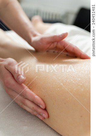 Therapist performs honey massage on client leg during wellness treatment. Therapist performs honey massage on client leg during wellness treatment. 140451481