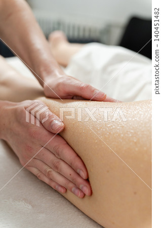 Therapist performs honey massage on client leg during wellness treatment. Therapist performs honey massage on client leg during wellness treatment. 140451482