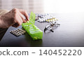 Middle aged caucasian man distributing scheduled dose of medication in dosette box 140452220