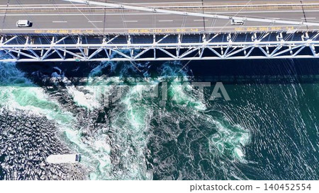 A spectacular aerial view of cars driving across the Great Naruto Bridge and sightseeing boats sailing across the Naruto Strait. A spectacular aerial view of cars driving across the Great Naruto Bridge and sightseeing boats sailing across the Naruto Strait. 140452554