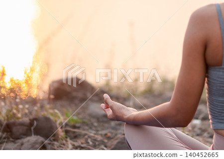 Close-up of a woman's hand in meditation mudra during outdoor yoga at sunset, showing mindful breathing, inner balance, calm focus, spiritual wellness, peaceful nature, and warm copy space. Close-up of a woman's hand in meditation mudra during outdoor yoga at sunset, showing mindful breathing, inner balance, calm focus, spiritual wellness, peaceful nature, and warm copy space. 140452665