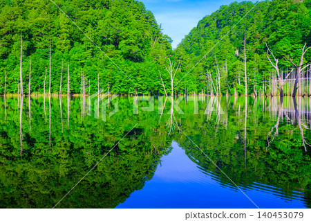 初夏清晨,陽光明媚:綿延至天然湖泊上游的層疊山脈,倒映在水中,宛如達摩不倒翁。 初夏清晨,陽光明媚:綿延至天然湖泊上游的層疊山脈,倒映在水中,宛如達摩不倒翁。 140453079