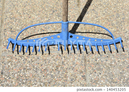 Blue plastic garden rake head on a stone tile background Blue plastic garden rake head on a stone tile background 140453205