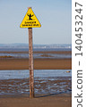 Bright yellow sinking mud warning sign on beach 140453247