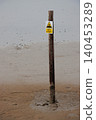 Danger sinking mud sign on pole in beach sand at low tide 140453289