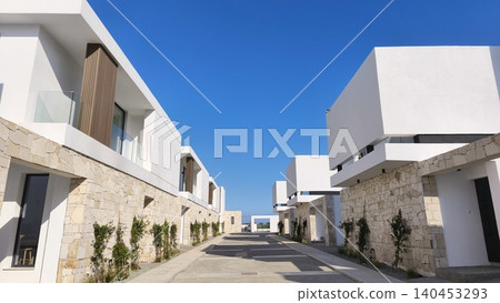 Modern luxury villa exterior with minimalist architecture, stone facade, panoramic windows, and landscaped courtyard in an upscale residential development 140453293