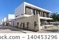 Contemporary luxury villas with clean geometric architecture, stone facades, and large windows under a clear blue sky, showcasing modern residential design and upscale living. 140453296