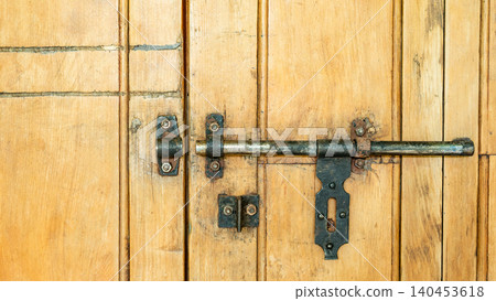 Rustic antique brass door bolt on wooden door panel 140453618