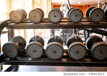 Set of dumbbells lined up by size on metal gym rack Set of dumbbells lined up by size on metal gym rack 140453627