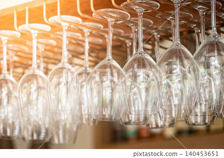 Empty wine glasses hang upside down on the rack over bar counter Empty wine glasses hang upside down on the rack over bar counter 140453651