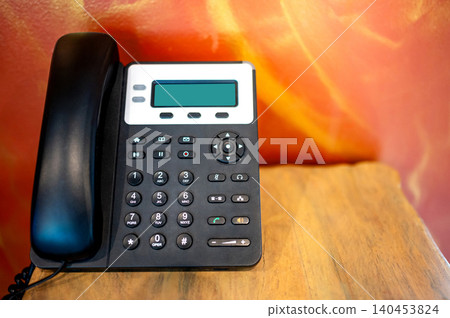 Black landline telephone on wooden table in hotel room 140453824