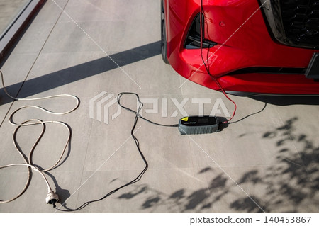 Red car battery charger connected recharging power Red car battery charger connected recharging power 140453867