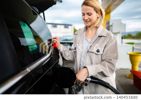 Woman refueling car with gasoline at gas station pump Woman refueling car with gasoline at gas station pump 140453880