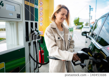 Woman refueling car with diesel at gas station Woman refueling car with diesel at gas station 140453886