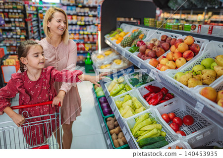 Mother and daughter choosing fresh produce in supermarket 140453935