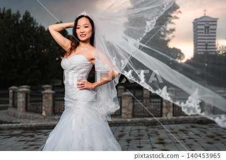 Chinese bride posing in wedding dress with veil flowing Chinese bride posing in wedding dress with veil flowing 140453965